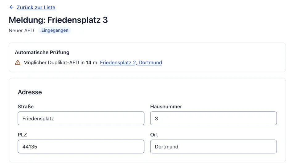 Prüfung einer Meldung „Friedensplatz 3“ (neuer AED, eingegangen): Die automatische Prüfung weist auf einen möglichen Doppeleintrag in 14 m Entfernung hin, mit Link zum Eintrag Friedensplatz 2; darunter die gemeldete Adresse.